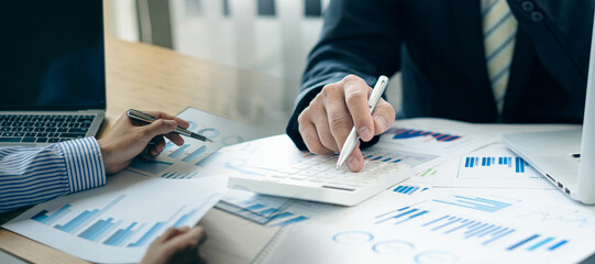 Business colleague working and analyzing financial figures on paper documents, accounts, contracts,...