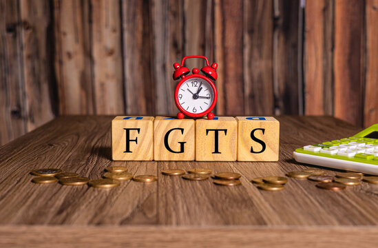 As iniciais FGTS de Fundo de Garantia do Tempo de Servi&ccedil;o com um rel&oacute;gio despertador, moedas e uma calculadora na composi&ccedil;&atilde;o.