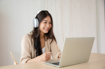 Young asian woman wearing headset while working on computer laptop at house. Work at home, Video conference, Video call, Student learning online class