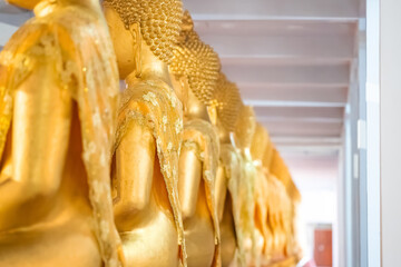 A Lot of Golden Statue of Buddha sitting meditated  in the row at Thailand Temple.