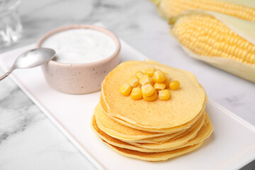 Tasty corn pancakes with sauce served on white marble table, closeup