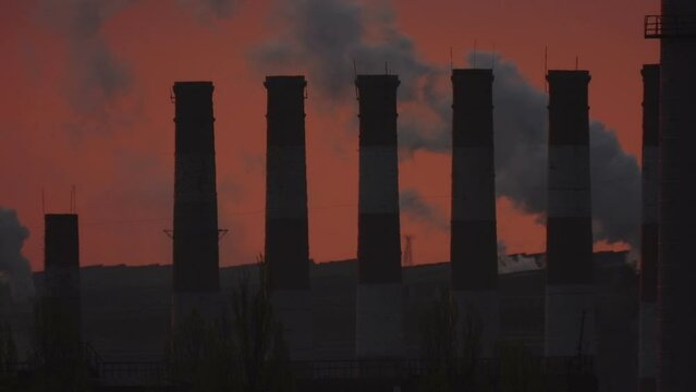 Smoking chimneys at dark dawn. Harmful substances are a side effect of metallurgy. Global smoke warming.