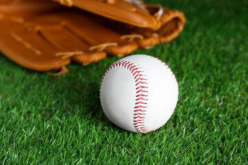 Catcher's mitt and baseball ball on green grass, closeup. Sports game