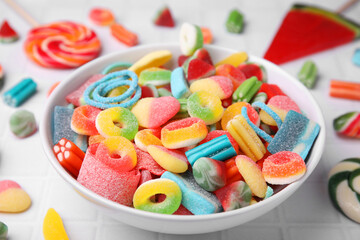 Bowl of tasty colorful jelly candies on white tiled table, closeup