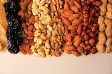 Mix of delicious dried nuts and fruits on beige background, flat lay