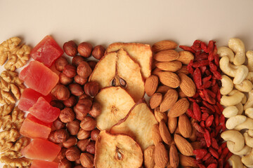 Mix of delicious dried nuts and fruits on beige background, flat lay