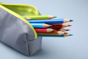 Fototapeta premium Many colorful pencils in pencil case on light grey background, closeup