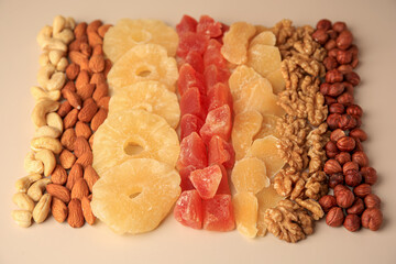 Different tasty nuts and dried fruits on beige background
