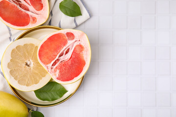 Different tasty pomelo fruits on white tiled table, flat lay. Space for text