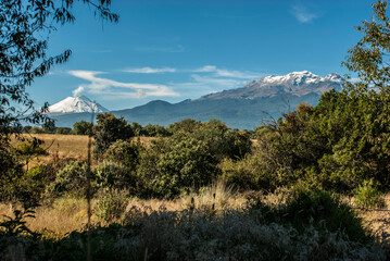 Paisaje de un campo y de fondo un volcán sacando humo. Querétaro, México. 
