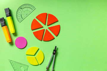 School stationery, fractions, rulers, pencils on green background. Back to school, fun education concept. Set of supplies for mathematics and for school. Close up