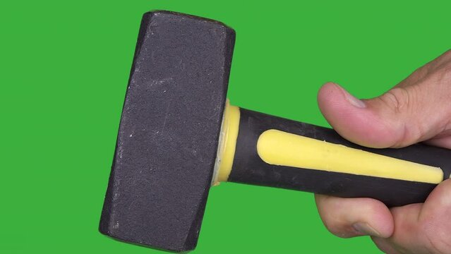 Hand holding a crack hammer isolated on a green background