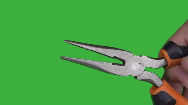 Hand holding long needle nose pliers isolated on a green background