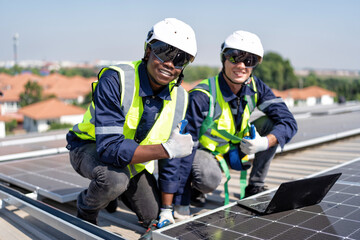 Engineer on rooftop kneeling next to solar panels photo voltaic check laptop for good installation