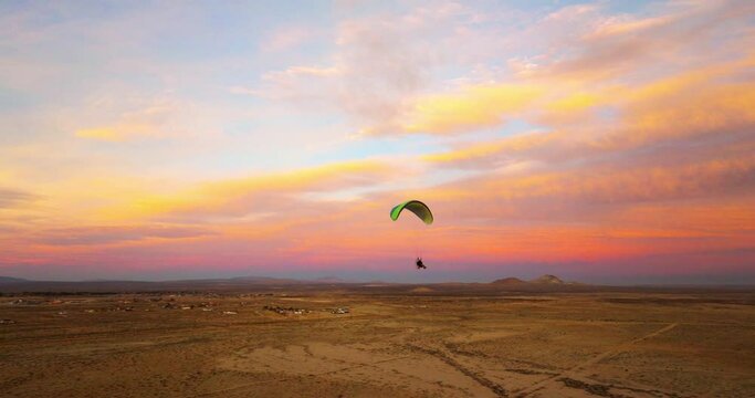 Powered paragliding over the Mojave Desert Landscape during an epic sunset - aerial drone follow