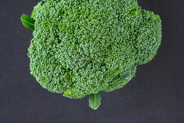 Fresh broccoli head with leaves on a black background, fresh, healthy, raw green superfood
