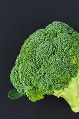 Fresh broccoli head with leaves on a black background, fresh, healthy, raw green superfood
