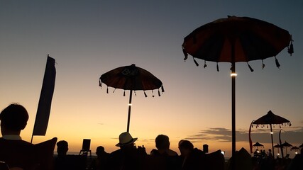 Silhouette People enjoying the sunset view on double six beach in Bali and sitting on sofa cushions...