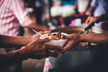 Concept of giving free food to the poor in the community : Volunteers handing out food to hungry...