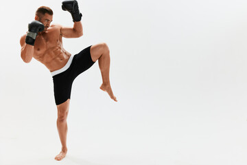 Man athletic bodybuilder poses in boxing gloves with nude torso abs in full-length background, boxing and martial arts. Advertising, sports, active lifestyle, light, competition, challenge concept. 