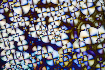 Colorful micro crystals in polarized light. Photo through a microscope - 557101548