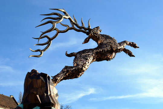 The wondrous or miracle deer statue in gold color shiny metal. Budapest, Hungary. December, 2022. jumping deer on hind legs. isolated sculpture. blue sky background.