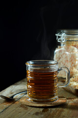 A Cup of freshly tea, escaping steam,warm soft light, darker background