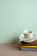 Stack of notebook and pen, cup of coffee on desk. mint wall background. workspace, copy space