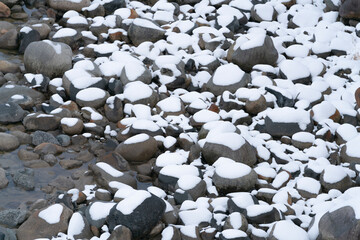 薄っすら雪が積もった河原の小石