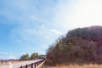 Fototapeta na wymiar よく晴れた2月に撮影した安曇野アートラインの橋と林