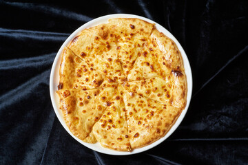 khachapuri in a white plate on black velvet