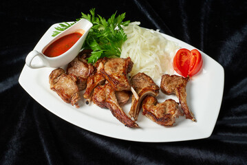 fried chicken legs and wings with fresh tomatoes and cucumbers on a black background