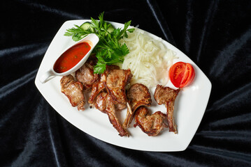 fried chicken legs and wings with fresh tomatoes and cucumbers on a black background