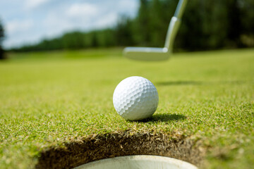 Hole on the golf course, next to a white ball