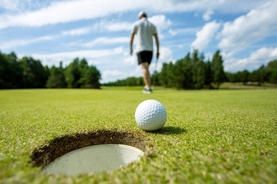 Hole on the golf course, next to a white ball