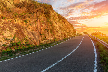 Fototapeta na wymiar Asphalt road and mountain natural landscape at sunset