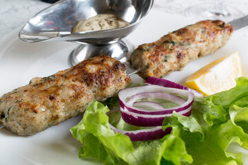 minced meat kebab with sauce, herbs and onions