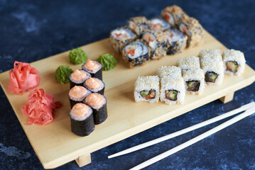 sushi, rolls on a light wooden tray on a blue background
