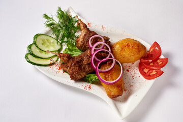 fried quail with potatoes, lettuce, cucumbers and tomatoes in a white plate, on a white background