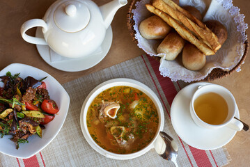 soup with meat on a bone, with salad, bread and tea