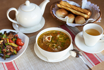 soup with meat on a bone, with salad, bread and tea