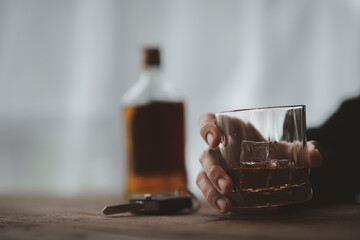 Man holding a glass of brandy, he is drinking brandy in a bar, drinking alcohol impairs driving ability and can damage health. The concept of drinking alcohol.