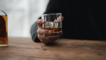 Man holding a glass of brandy, he is drinking brandy in a bar, drinking alcohol impairs driving ability and can damage health. The concept of drinking alcohol.