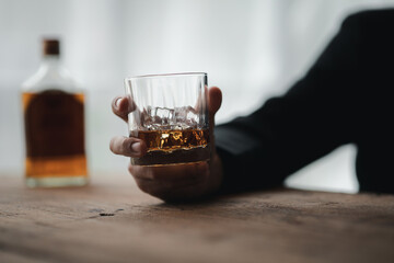 Man holding a glass of brandy, he is drinking brandy in a bar, drinking alcohol impairs driving ability and can damage health. The concept of drinking alcohol.