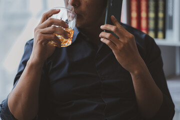 Man holding a glass of brandy, he is drinking brandy in a bar, drinking alcohol impairs driving ability and can damage health. The concept of drinking alcohol.