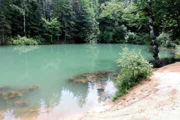 A view of an azure lakelet among trees in Rudawy Janowickie, Sudetes mountains, Poland - obrazy, fototapety, plakaty