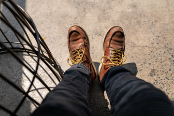 Men fashion in leather boots, Close up view on man's legs in black jeans and brown leather boots, Toned picture.