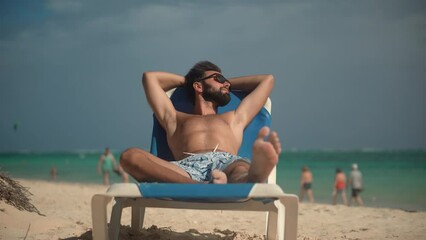 tanned man sunbathing in sun lounger on beach 