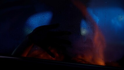 Unrecognizable couple passionately kissing on a backseat of a car, hand is pressing against the window