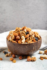Raw mixed nuts on gray background. Walnuts, almonds, hazelnuts and raisins in a coconut bowl. close up
